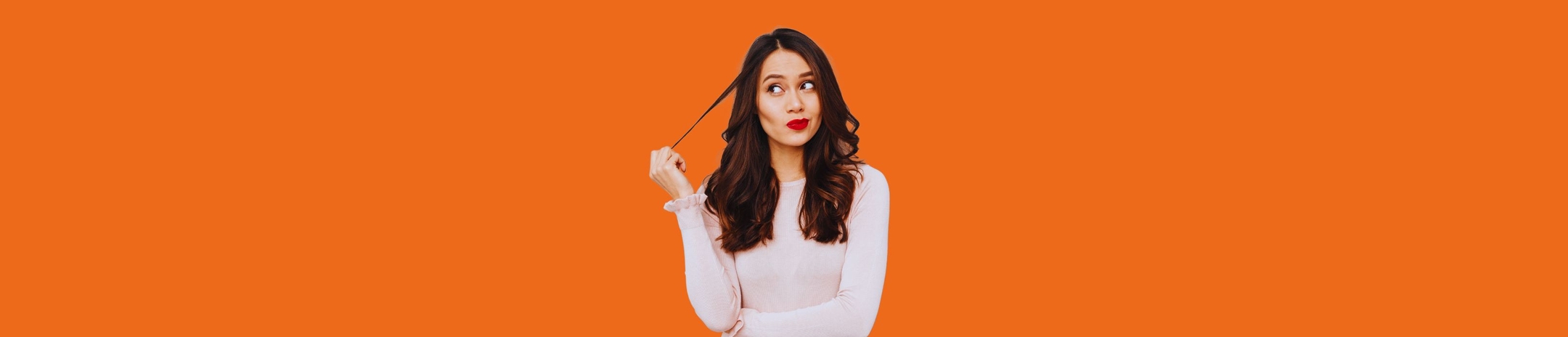 Girl in white long sleeved top in front of an orange background